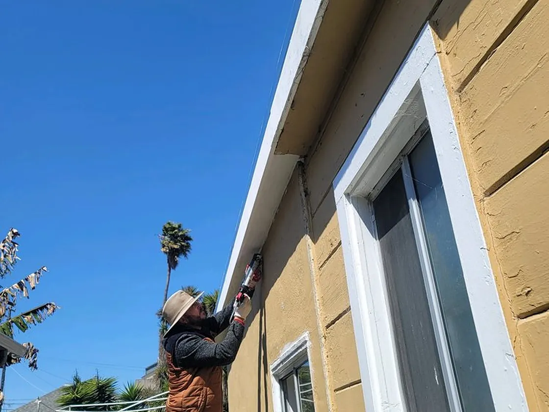 Roofer working at the eave line where the roof edge meets the gutter and fascia