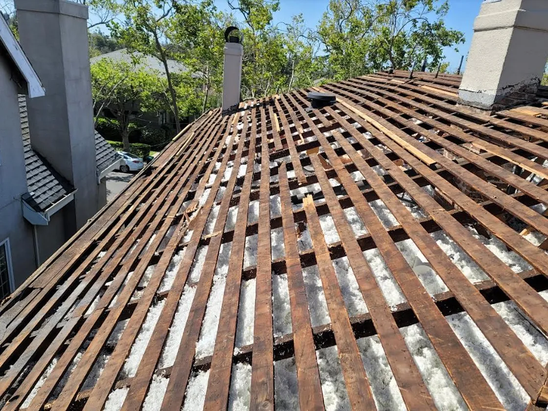 Roof tear off in progress exposing the original skip sheathing on an older home