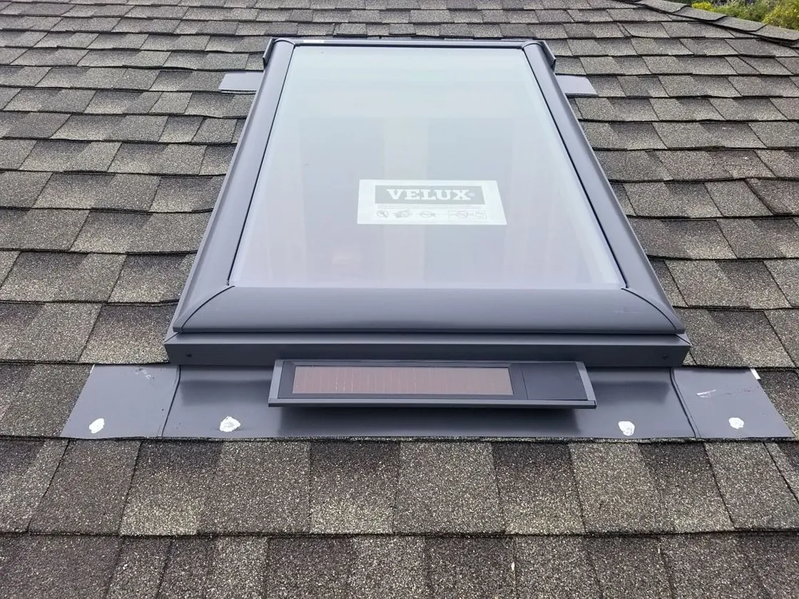 Skylight set cleanly into an asphalt shingle roof with tight flashing work around the perimeter